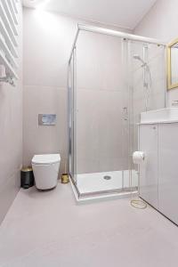ein weißes Bad mit einer Dusche und einem WC in der Unterkunft Novel NeW in Warschau