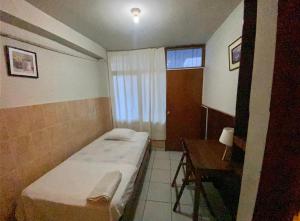 Happy Day Pucallpa في بوكالبا: غرفة صغيرة بها سرير ومكتب