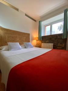ein Schlafzimmer mit einem großen Bett und einer roten Decke in der Unterkunft La Ventanita Del Campo in La Cavada