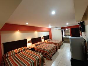 2 Betten in einem Hotelzimmer mit roten Wänden in der Unterkunft Hotel Villa de Altamira in Altamira