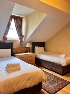 a attic bedroom with two beds and a window at Beech Mount Grove Suites in Liverpool