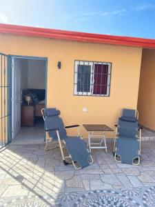 eine Terrasse mit Stühlen und einem Tisch vor einem Haus in der Unterkunft Villa Bellevue in San Felipe de Puerto Plata