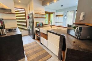 a large kitchen with a sink and a microwave at Private Garden Villa in Las Terrenas
