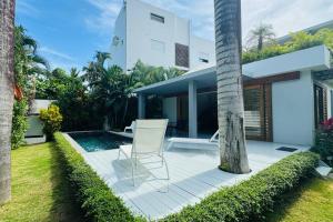 una silla blanca sentada en un patio junto a una piscina en Private Garden Villa en Las Terrenas