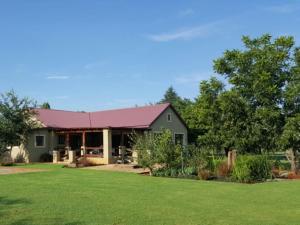 ein grünes Haus mit rotem Dach und Hof in der Unterkunft Arum Lily Eloff in Delmas