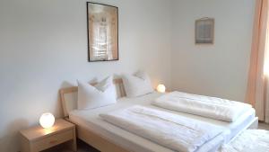 um quarto com 2 camas com lençóis brancos e almofadas em Ferienwohnungen Geier em Niederalteich