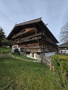 a large wooden building with a fence in front of it at Fuchswirt Kelchsau Landgasthof-Hotel in Hopfgarten im Brixental