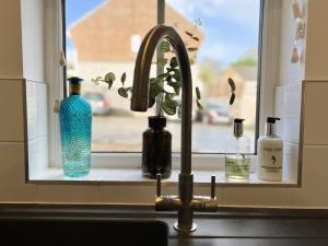 a kitchen sink with a window with bottles on it at Cowes Town House in Cowes