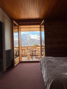una camera da letto con balcone affacciato su una montagna di Hôtel Restaurant La Pendine a Puy-Saint-Vincent