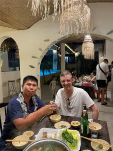 two men sitting at a table with food at Red Sands Pool Villa in Phan Thiet