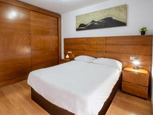 a bedroom with a large white bed and wood paneling at BHost - María Auxiliadora in Córdoba