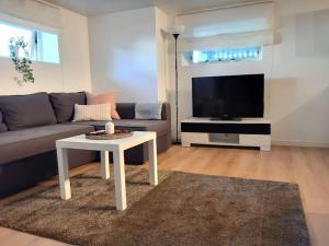 a living room with a couch and a table and a tv at By the sea apartment in Stavanger