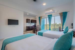 ein Hotelzimmer mit 2 Betten und einem Balkon in der Unterkunft BnB Homes, Technopark, Trivandrum in Kazhakuttam