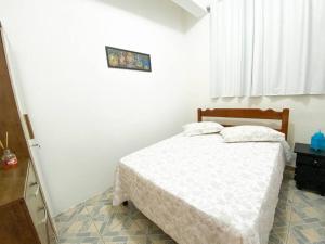 a bedroom with a white bed and a window at Casinha Quadra Mar a 10 min do Beto Carrero! in Penha