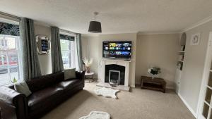 a living room with a black leather couch and a fireplace at Hummingbird House in Cockermouth