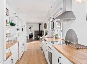 Cozy Cottage With Wilderness Bath في Føllenslev: مطبخ أبيض كبير مع أرضيات خشبية ودواليب بيضاء