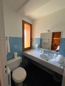 La salle de bains est pourvue de toilettes et d'un lavabo avec miroir. dans l'établissement Hôtel Restaurant La Pendine, à Puy-Saint-Vincent