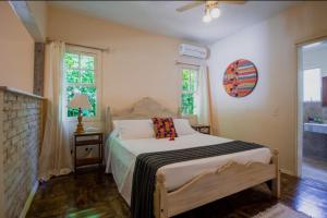 a bedroom with a bed and two windows at Pousada Villa Allegra in Tiradentes