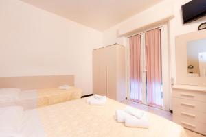 a white bedroom with two beds and a dresser at Hotel Galileo in Rimini