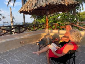 潘切的住宿－Red Sands Pool Villa，坐在桌子下伞下的男人和女人