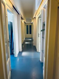 an empty hallway with blue floors and white doors at Maya Rooms in Milan