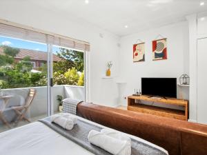 a bedroom with a bed and a tv and a balcony at Fairmile Urban Oasis in Cape Town