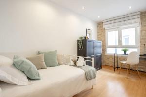 een slaapkamer met een groot wit bed en een stoel bij Escalera 12 in Gijón