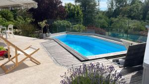 a swimming pool in a garden with a chair and a table at Chambre dans jolie nature in Auxi-le-Château +6 photos