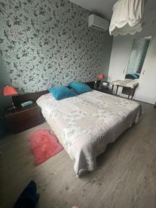 a bedroom with a large bed with blue pillows at Chambre dans jolie nature in Auxi-le-Château