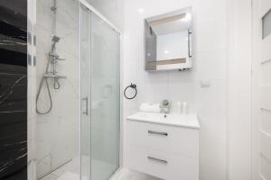 een witte badkamer met een douche en een wastafel bij Kapitański Mostek Pet-Friendly Apartment Kołobrzeg by Renters in Kołobrzeg