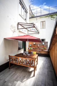 un patio con una mesa de madera y una sombrilla roja en Cozy apartment in heart of Maribor / big terrace en Maribor