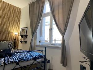 a bedroom with a bed and a window and a television at Sparrow Apartment in Kazimierz in Krakow