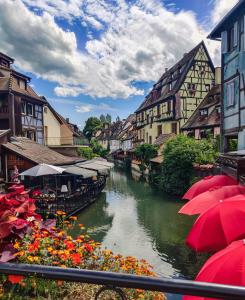 a river with buildings and red umbrellas in a town at Travel Homes - Tanneur 6, heart of Petite Venise in Colmar +19 photos
