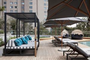 a group of lounge chairs and umbrellas next to a pool at The Capital On the Park Self-Catering Apartments in Johannesburg
