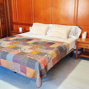 a bed with a colorful quilt and two tables at Can Carreras de Sant Jaume in Sant Jaume de Llierca