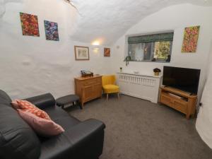 a living room with a couch and a television at Le Durkestrete Cellar in Haverfordwest