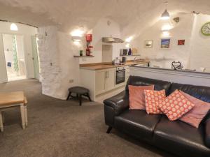 a living room with a leather couch and a kitchen at Le Durkestrete Cellar in Haverfordwest
