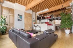 a living room with a leather couch and a kitchen at Suite Lanterne - Hypercentre 2CH 2SDB in Lyon