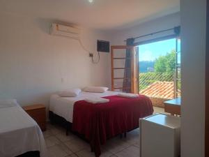 a room with two beds and a window with a view at Pousada Casablanca Águas de São Pedro in Águas de São Pedro