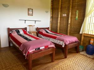 twee bedden in een kamer met houten vloeren bij Bungalows Ayampe in Ayampe