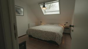 a small bedroom with a bed and a window at Gastenverblijf 't Hof van Eden in Wingene