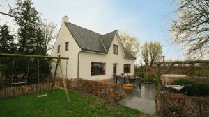 una casa blanca con techo negro en Gastenverblijf 't Hof van Eden, en Wingene