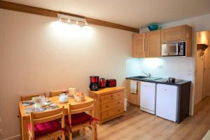 a small kitchen with a small table and a kitchen with a refrigerator at Andromede - 35 - Studio coeur station - 4 pers in Les Deux Alpes