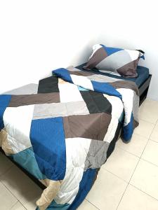 a bed with a blue and white quilt on it at Indera Sempurna Ruma Aisya in Kuantan
