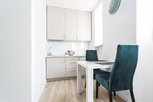 a kitchen with a white table and two green chairs at Novel NeW in Warsaw