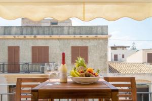 a table with a bowl of fruit and a bottle of wine at Appartamenti Leone1 in San Vito lo Capo