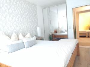a bedroom with a white bed and a mirror at Ferienwohnungen Haus Paradies in Sankt Englmar