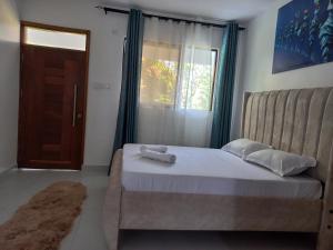 Schlafzimmer mit einem Bett, einem Fenster und einer Tür in der Unterkunft Ika homes in Nyali