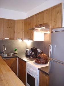 cocina con armarios de madera y nevera blanca en L'Oustal d'Adèle proche Canal du Midi et Moissac, en Saint-Nicolas-de-la-Grave