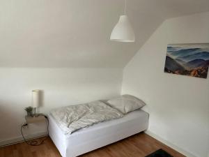 a bed in a white room with a lamp at Schöne Zimmervermietung für Monteure geeignet ! Direkt am Kanal mit Gartennutzung! in Hamm